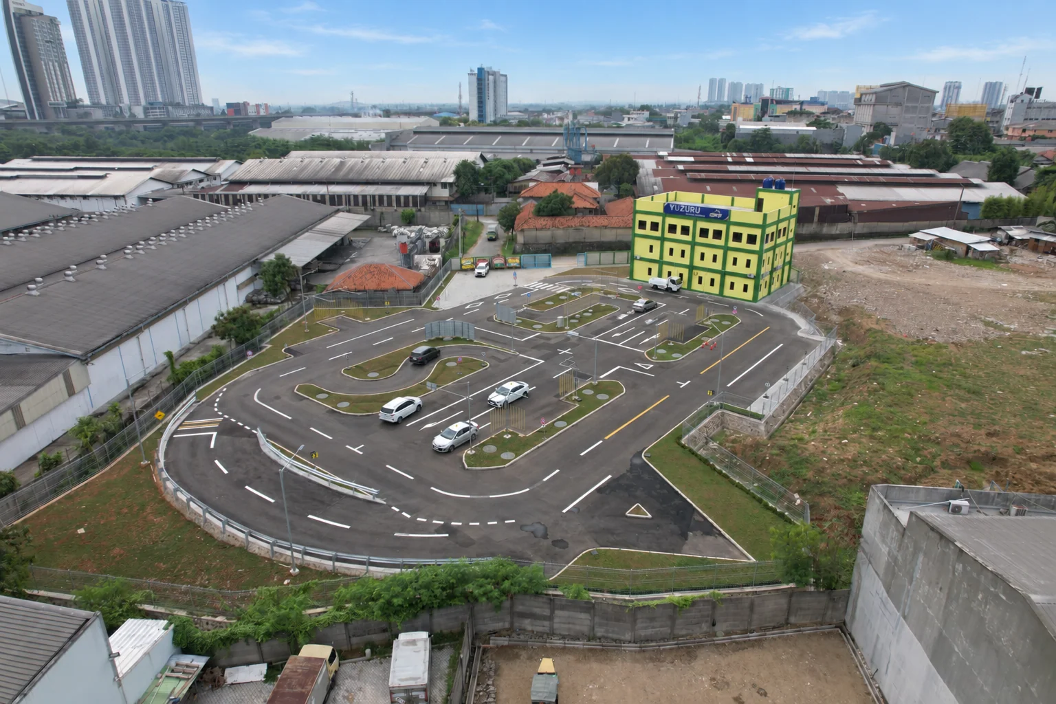 YUZURU DRIVING SCHOOLの校舎と、車両が走る教習コースの空撮