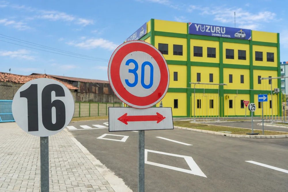 教習コースの速度制限30の標識と、青空を背景にしたYUZURU DRIVING SCHOOLの校舎